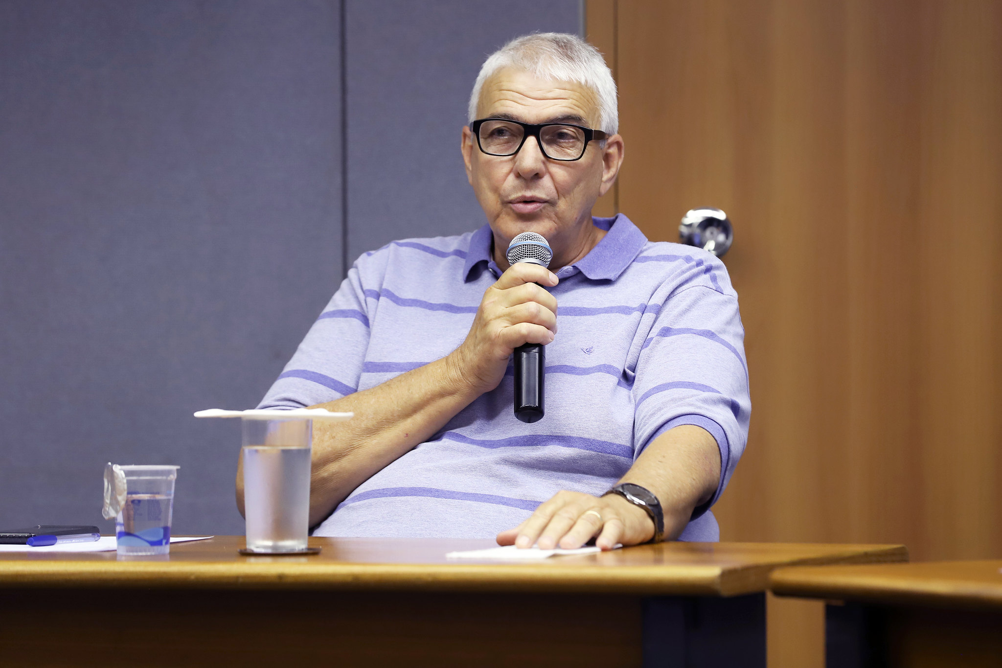 Fotografia do secretário Ernesto Dimas Paulella, sentado, falando ao microfone