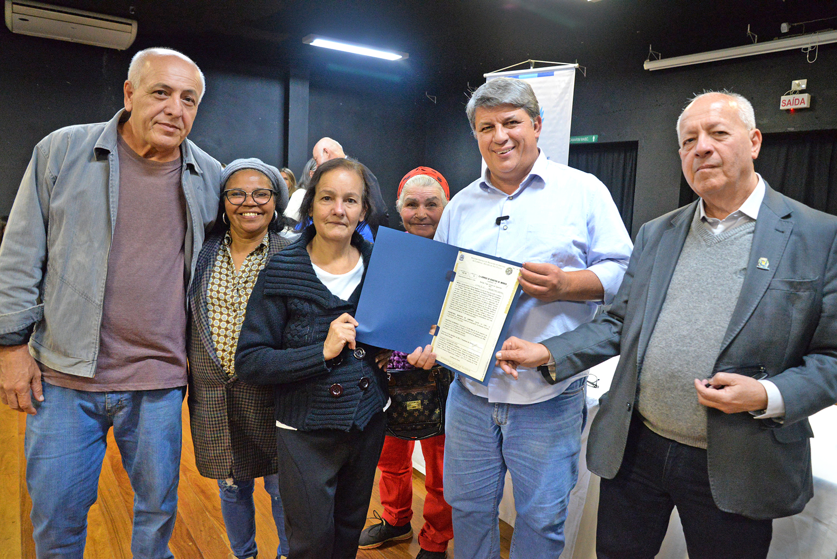 Moradora recebe escritura de imóvel