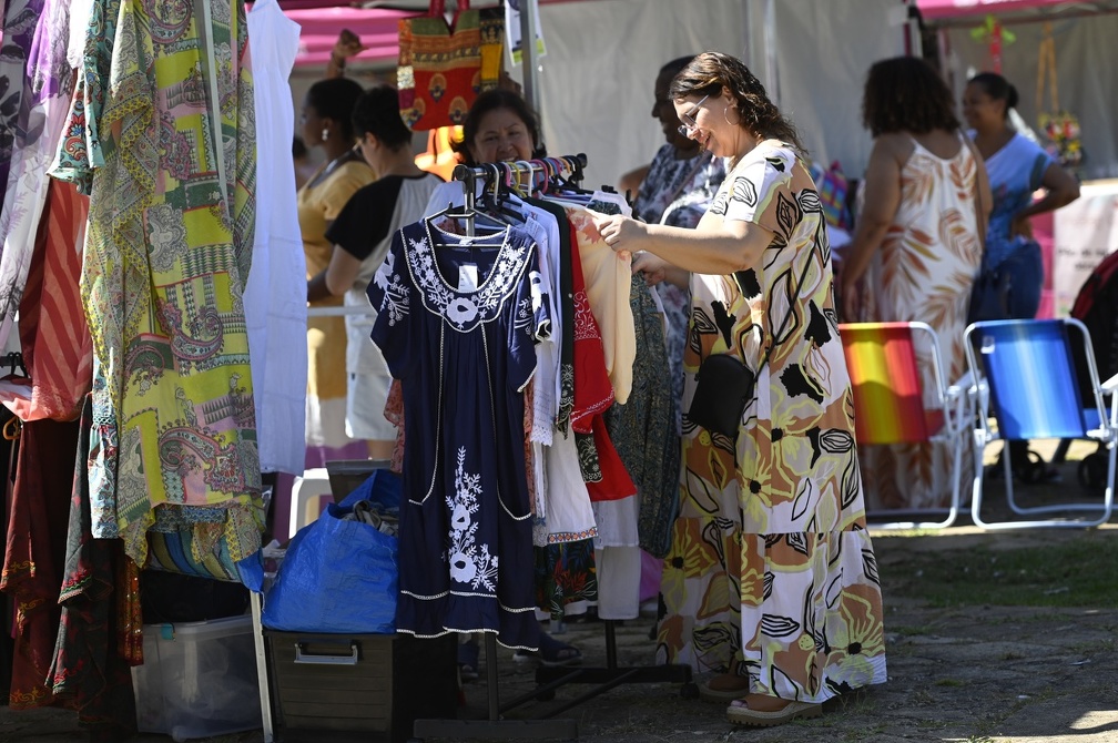 Consumidora confere roupa em banca da Feira das Mulheres Empreendedoras