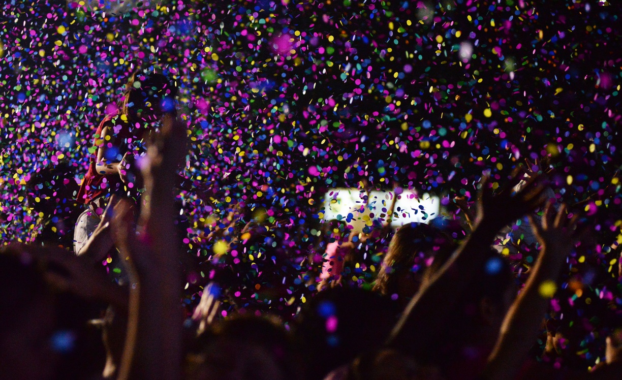 Chuva de papel picado colorido, bexigas, serpentina e até pipoca caem sobre o público