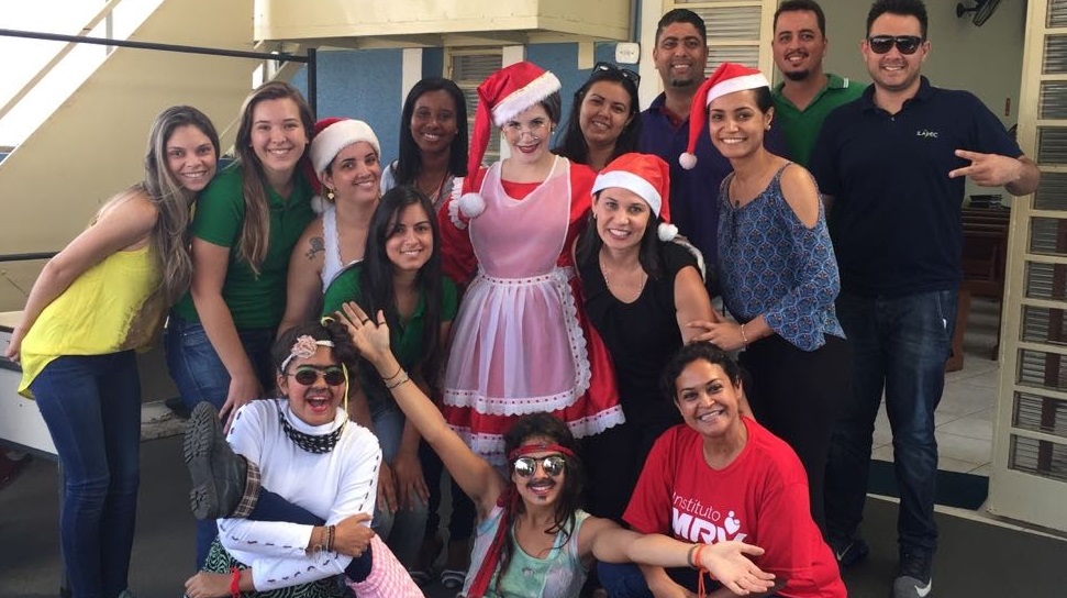 Lígia em evento de Natal (na foto, agachada vestindo camiseta vermelha)