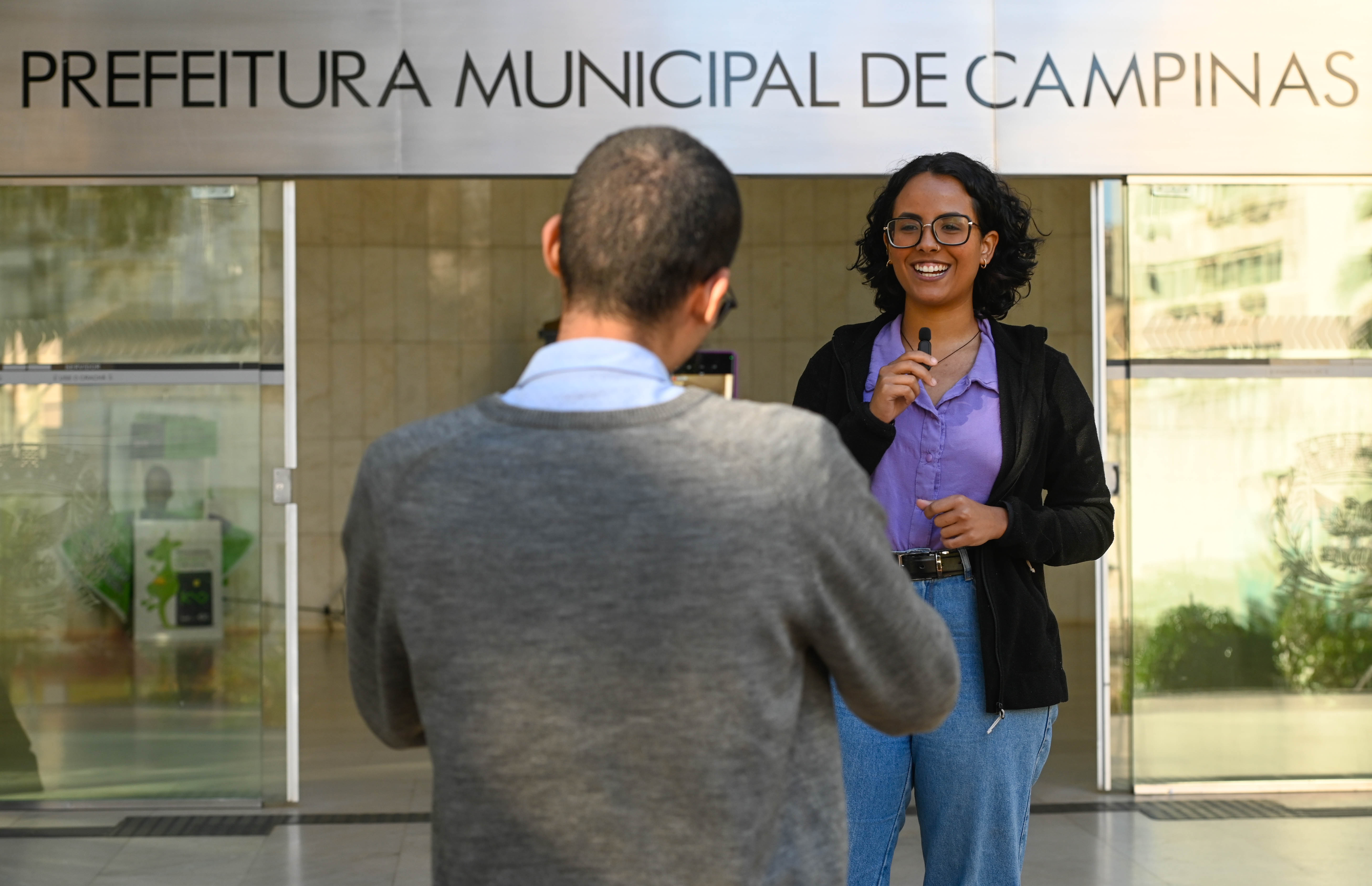 Rogério Capela Maria Vitória Porto e Daniel Ribeiro, estagiários de Jornalismo, gravam vídeo na entrada do Paço Municipal; há vagas para comunicação