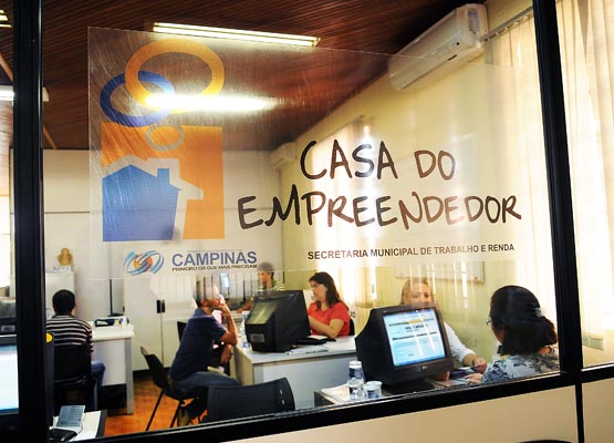 Imagem através de vidro mostra servidores da Casa do Empreendedor atendem pessoas interessadas em aderir ao MEI