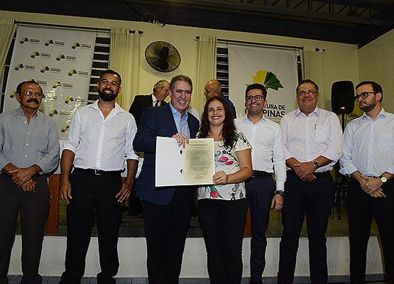 Moradora recebe documento das mãos do prefeito