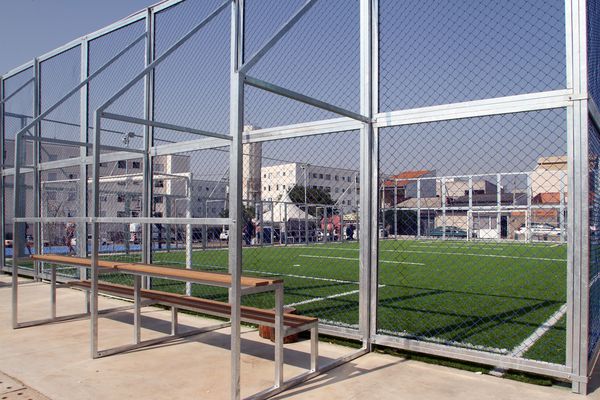 Campo de futebol society com grama sintética e alambrado