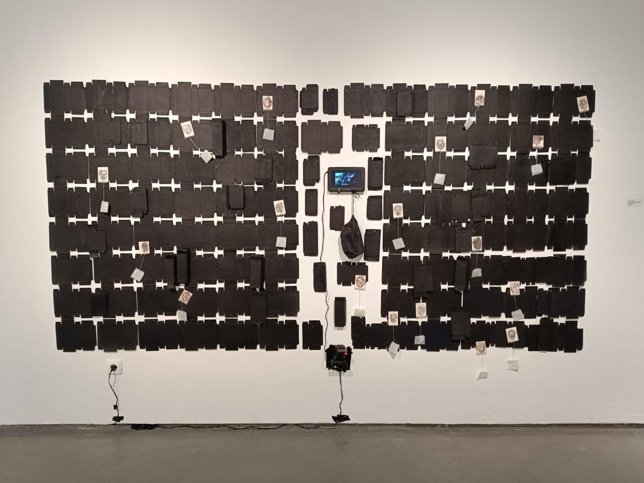 Caixas de medicamentos, saquinhos de chá, desenhos, tecido e dipsositivos multimidia na obra "Campo de forças" de Marta Strambi