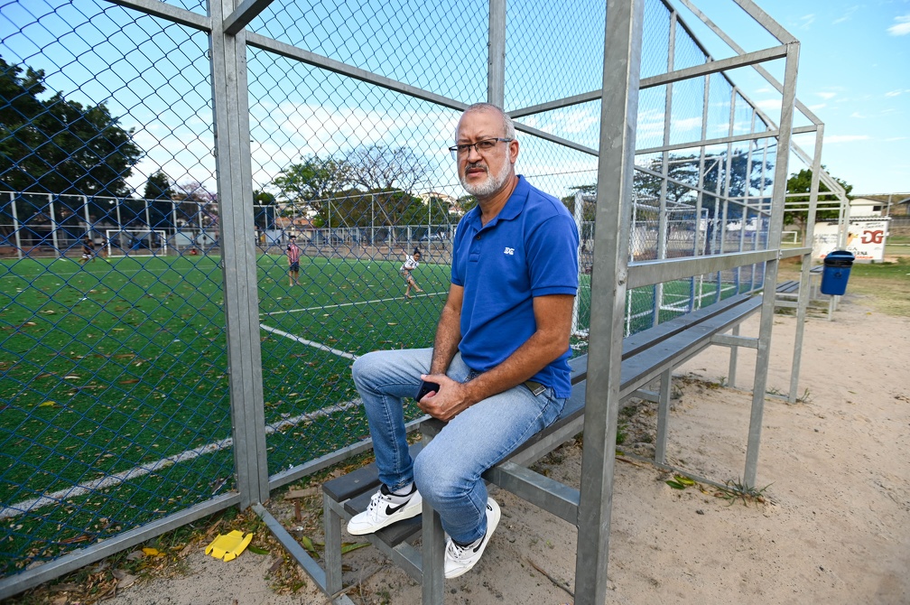 a foto mostra um homem sentado próximo a um campo